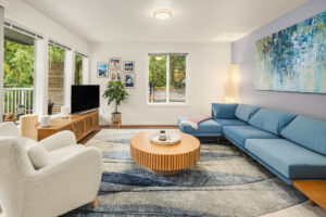 Contemporary apartment living room with natural light, modern furniture, and balcony views at Wildwood Apartment Homes in Issaquah, Washington.