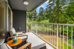 Apartment balcony with seating and scenic views of lush greenery at Wildwood Apartment Homes in Issaquah, Washington.