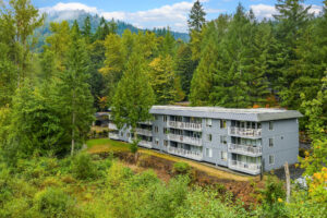 Exterior of Wildwood Apartment Homes building with multiple balconies, surrounded by trees and greenery in Issaquah, Washington.